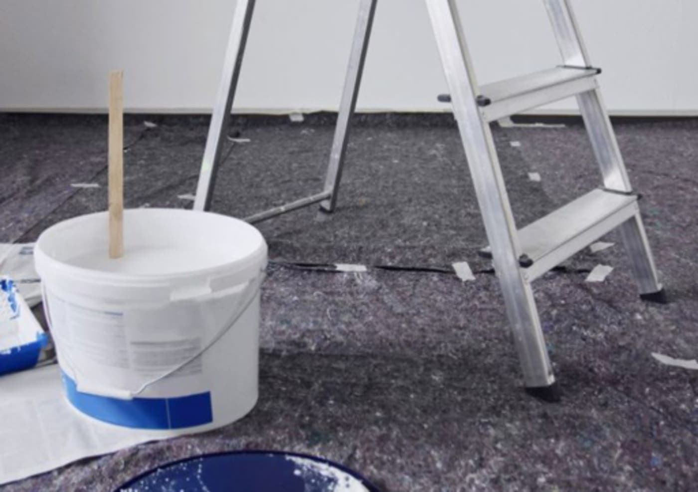 (Moqueta y herramientas sobre suelo protegido durante pintura)
