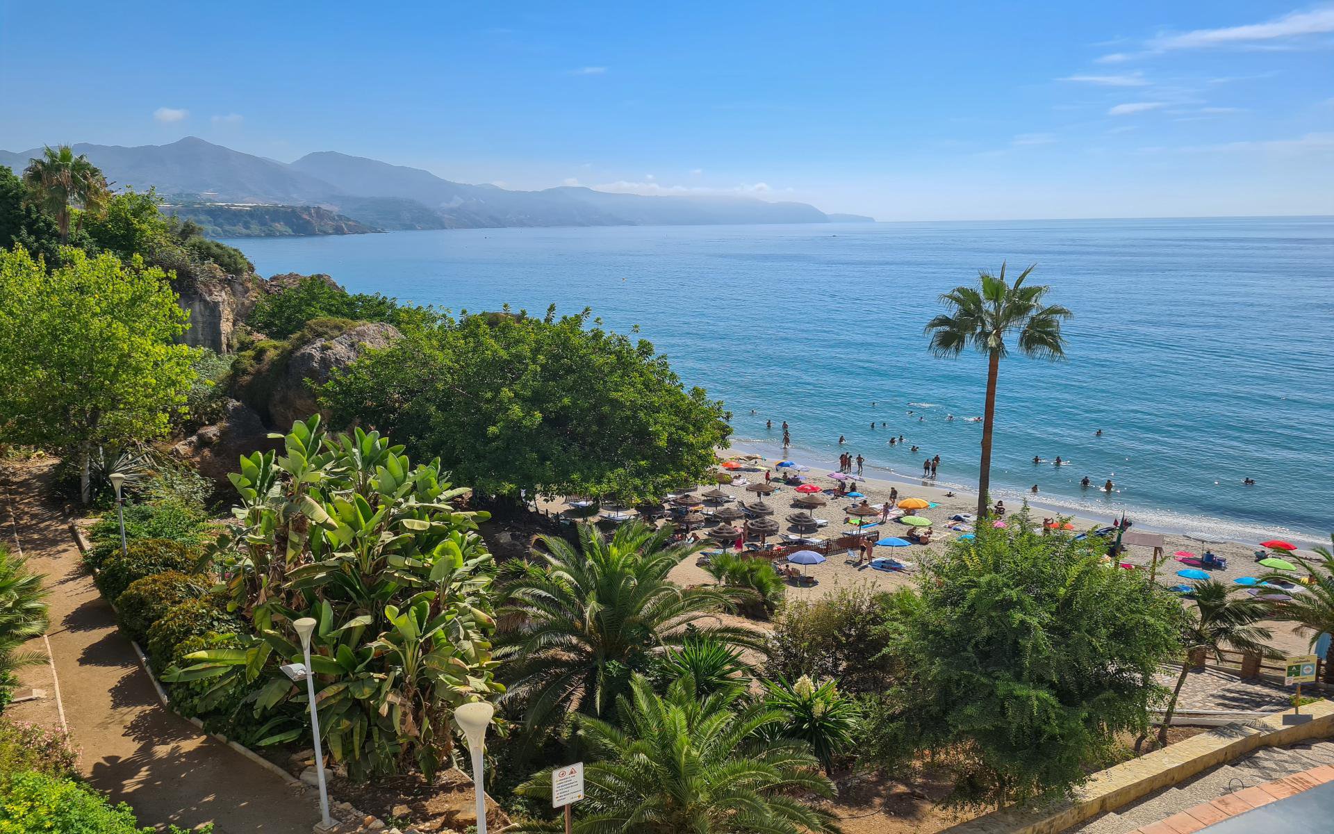 Jardín mediterráneo con vegetación cuidada frente a playa y costa de Málaga